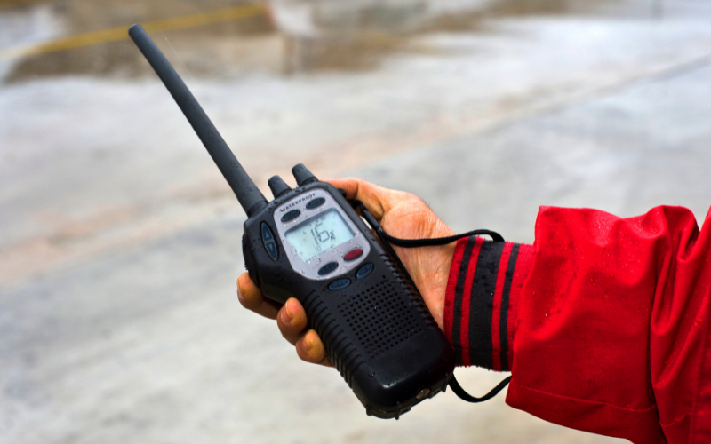 Handheld VHF radio in use, displaying frequency settings, highlighting its role in 2-way radio communication solutions.